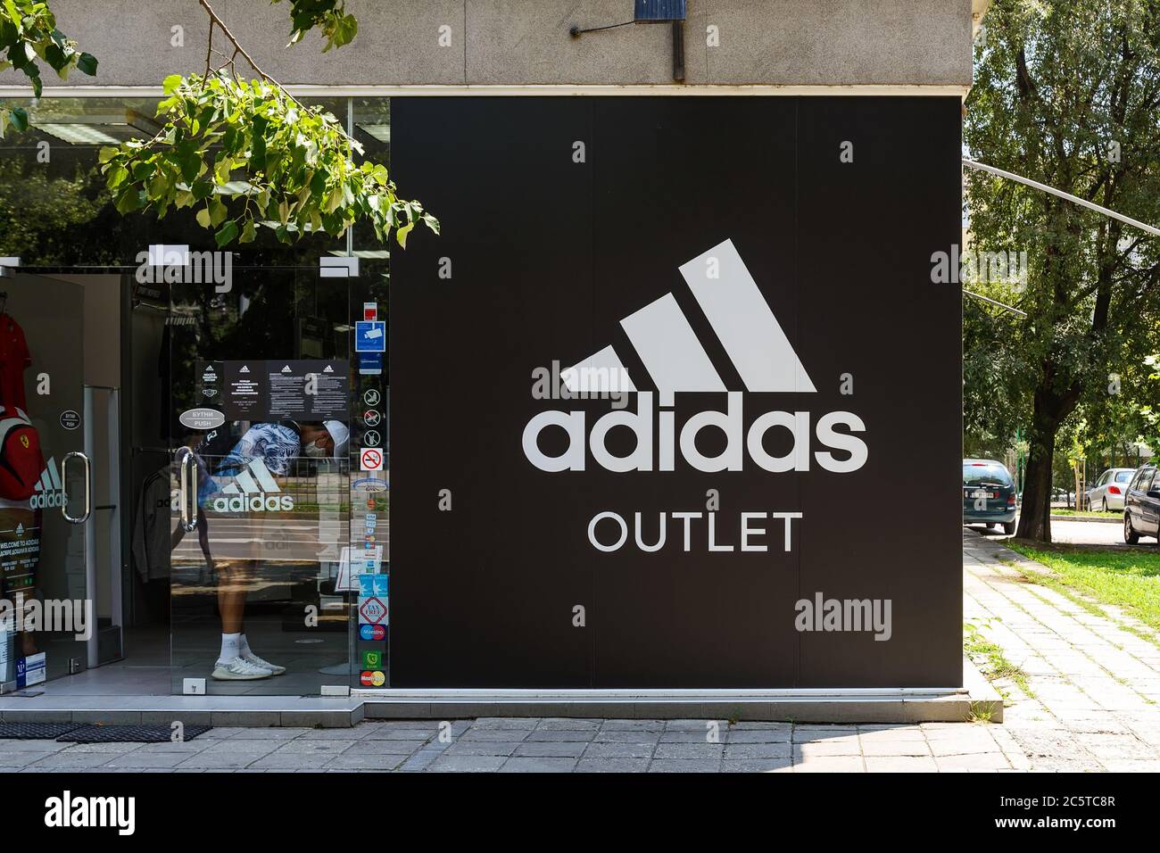 Varna, Bulgaria, 01 de julio de 2020. a la tienda outlet desde una calle de la ciudad en un soleado día de verano. logo Adidas signo de brend