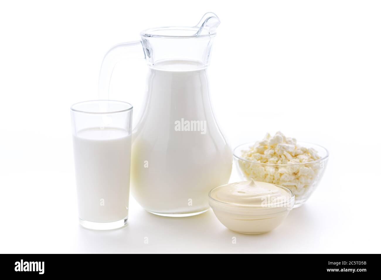 Leche fresca de vaca en un vaso sobre fondo blanco con una cuajada útil y crema agria sobre fondo blanco. Deliciosos productos lácteos. Foto de stock