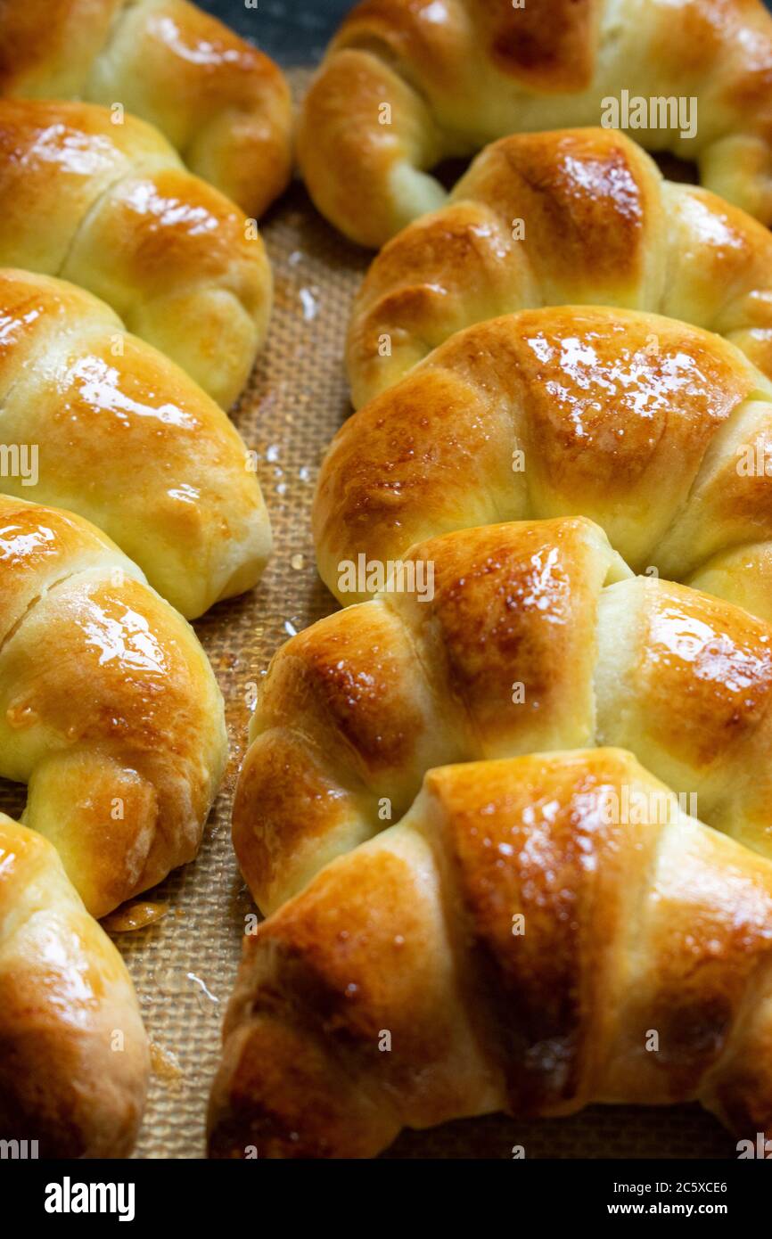 Croissants argentinos, medialunas de Manteca sobre una alfombrilla de silicona. Vertical Foto de stock