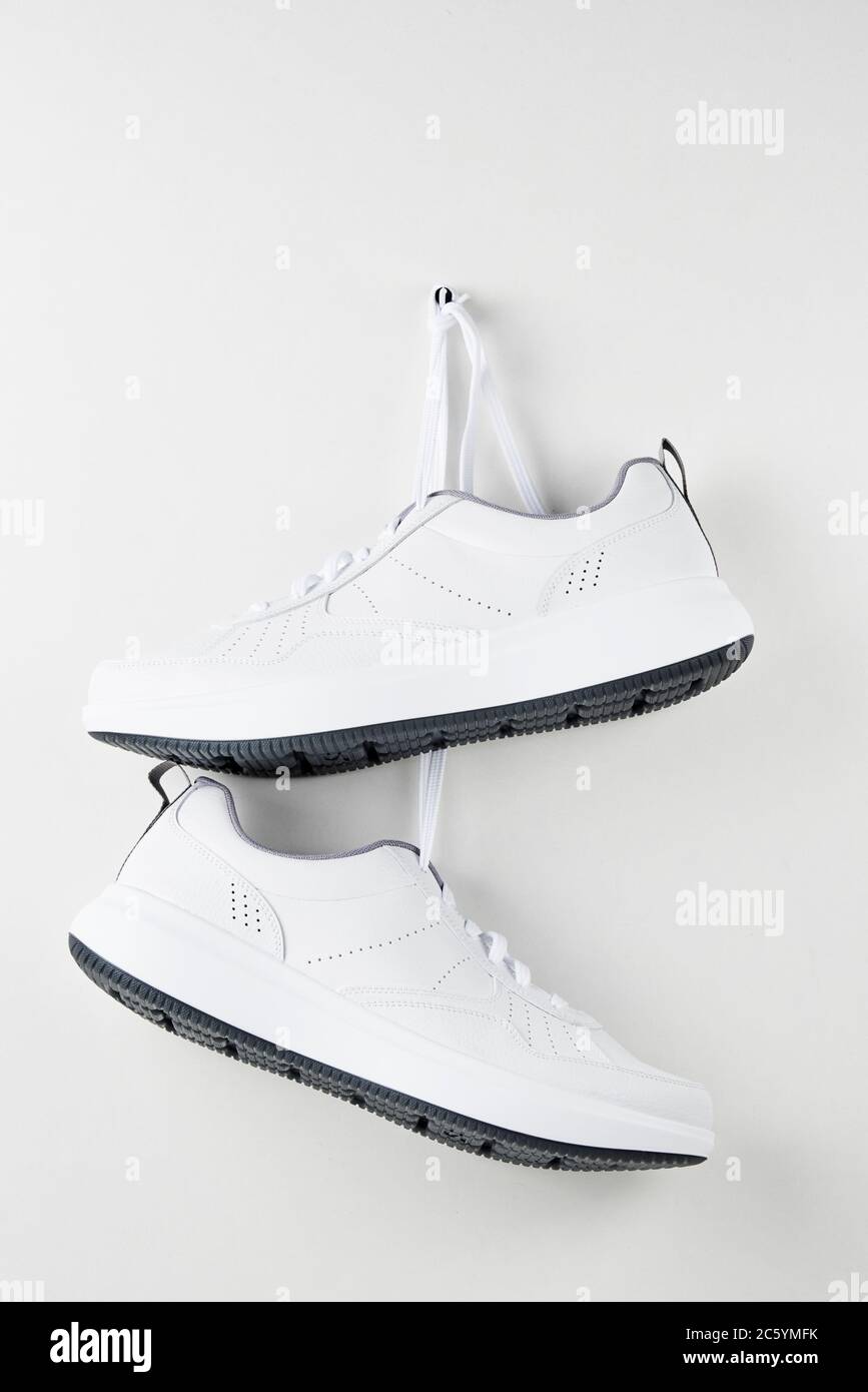 Dos sneakers blancas de hombre colgadas en la pared. Moda zapatos  deportivos con estilo, primer plano Fotografía de stock - Alamy