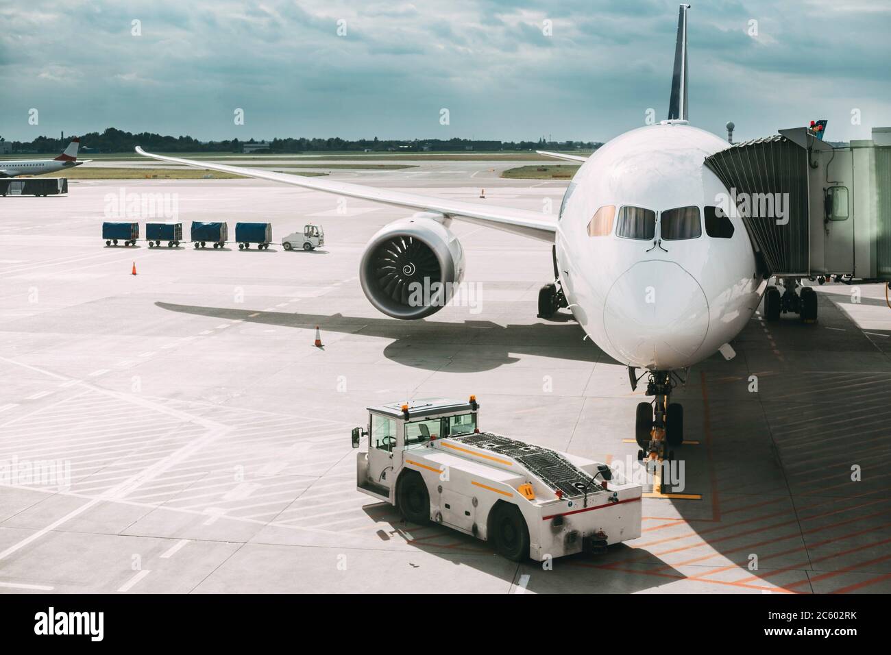 Plano de aviones de pasajeros de embarque en la terminal del aeropuerto. Tractor de remolque de aeronaves y el espanto carretilla cerca del avión. Foto de stock