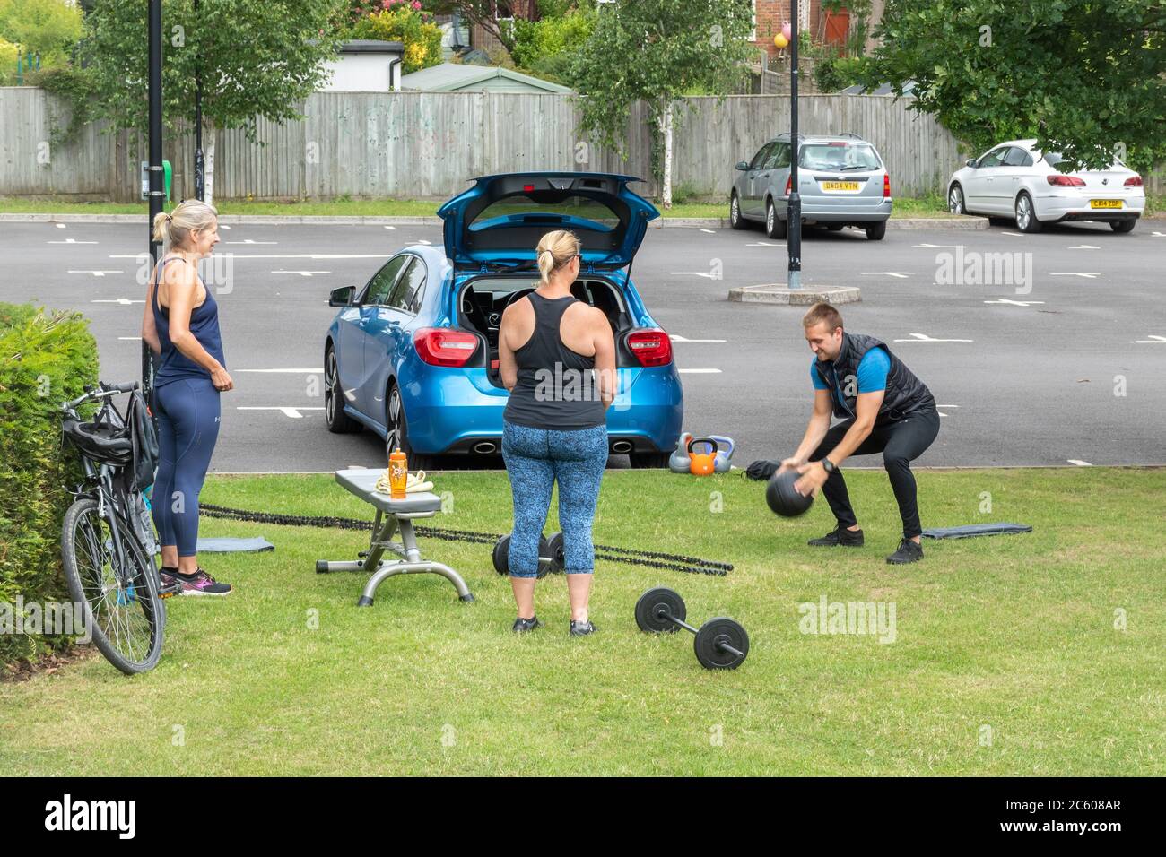 Entrenador personal trabajando fuera con dos mujeres con equipo de ejercicio durante la pandemia de covid-19 coronavirus, Reino Unido, 2020 Foto de stock