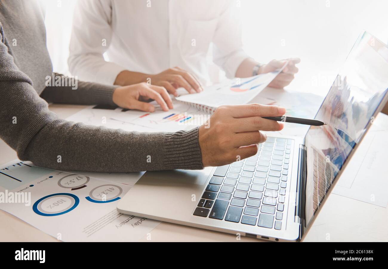 Equipo de negocios dos colegas trabajando con ordenador, tableta digital, discutiendo y analizando el mercado de valores gráfico de negociación con datos de gráfico de acciones, financia Foto de stock