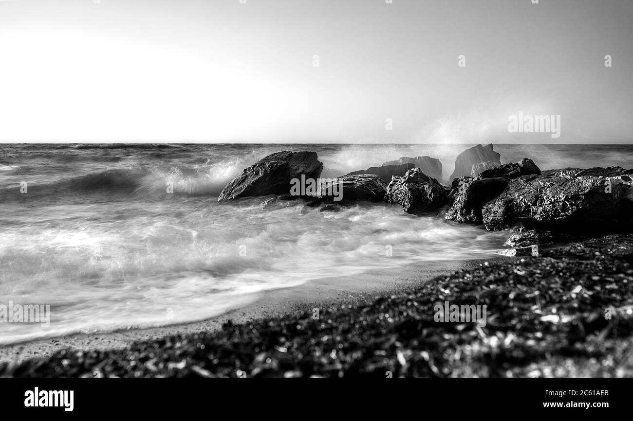 Fotografiar las olas que golpearon las rocas en un clima tormentoso con una larga exposición Foto de stock