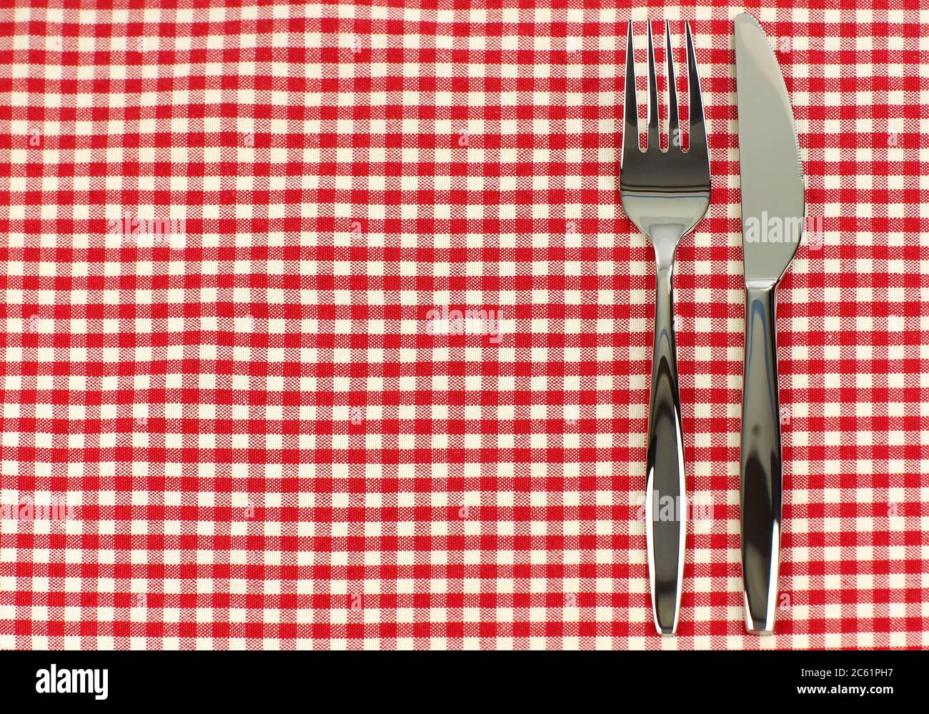 cuchillo brillante y tenedor en un mantel de cuadros rojo y blanco Foto de stock