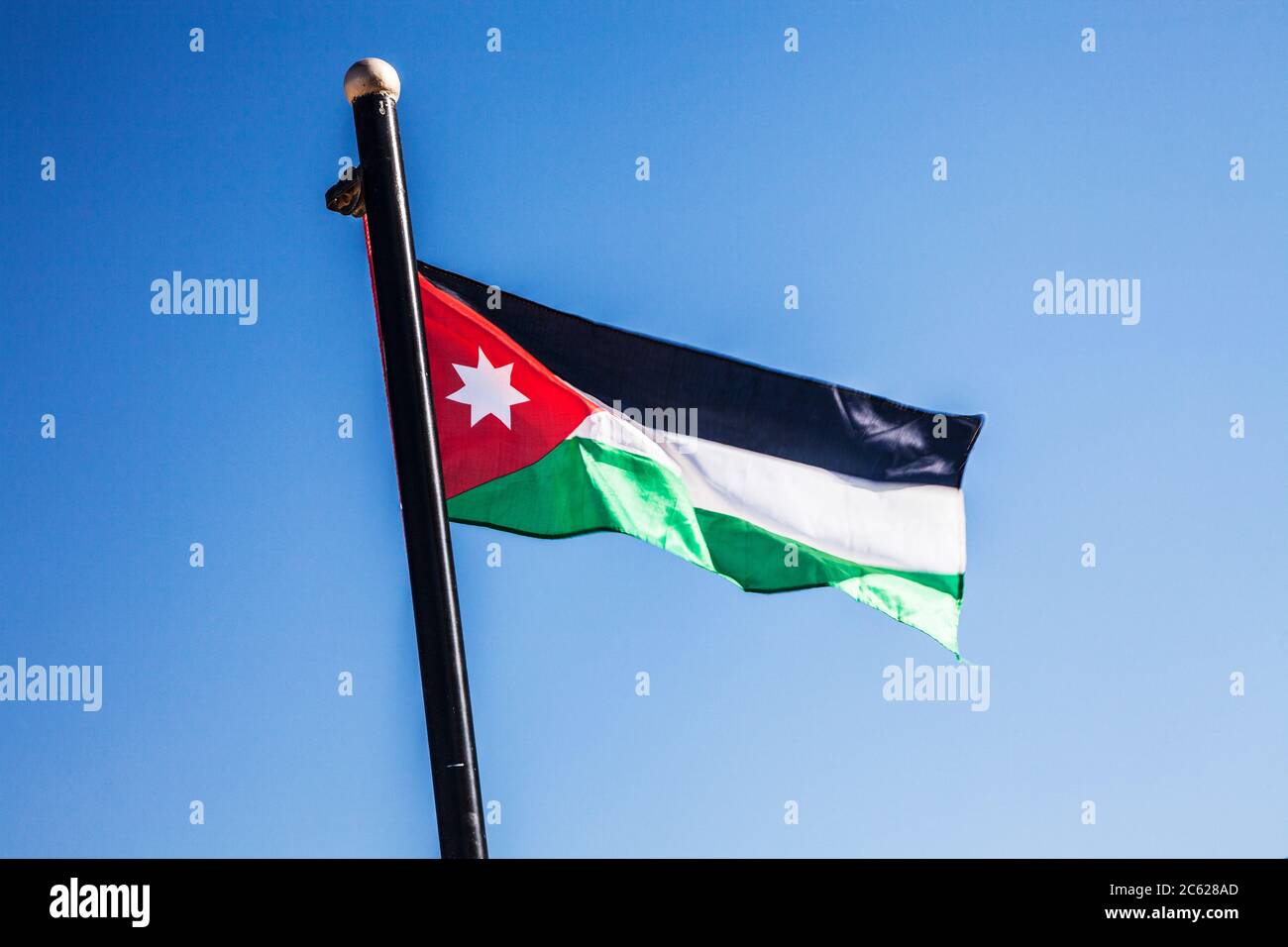 Una bandera jordana que revolotea en la brisa contra un cielo de verano. Foto de stock