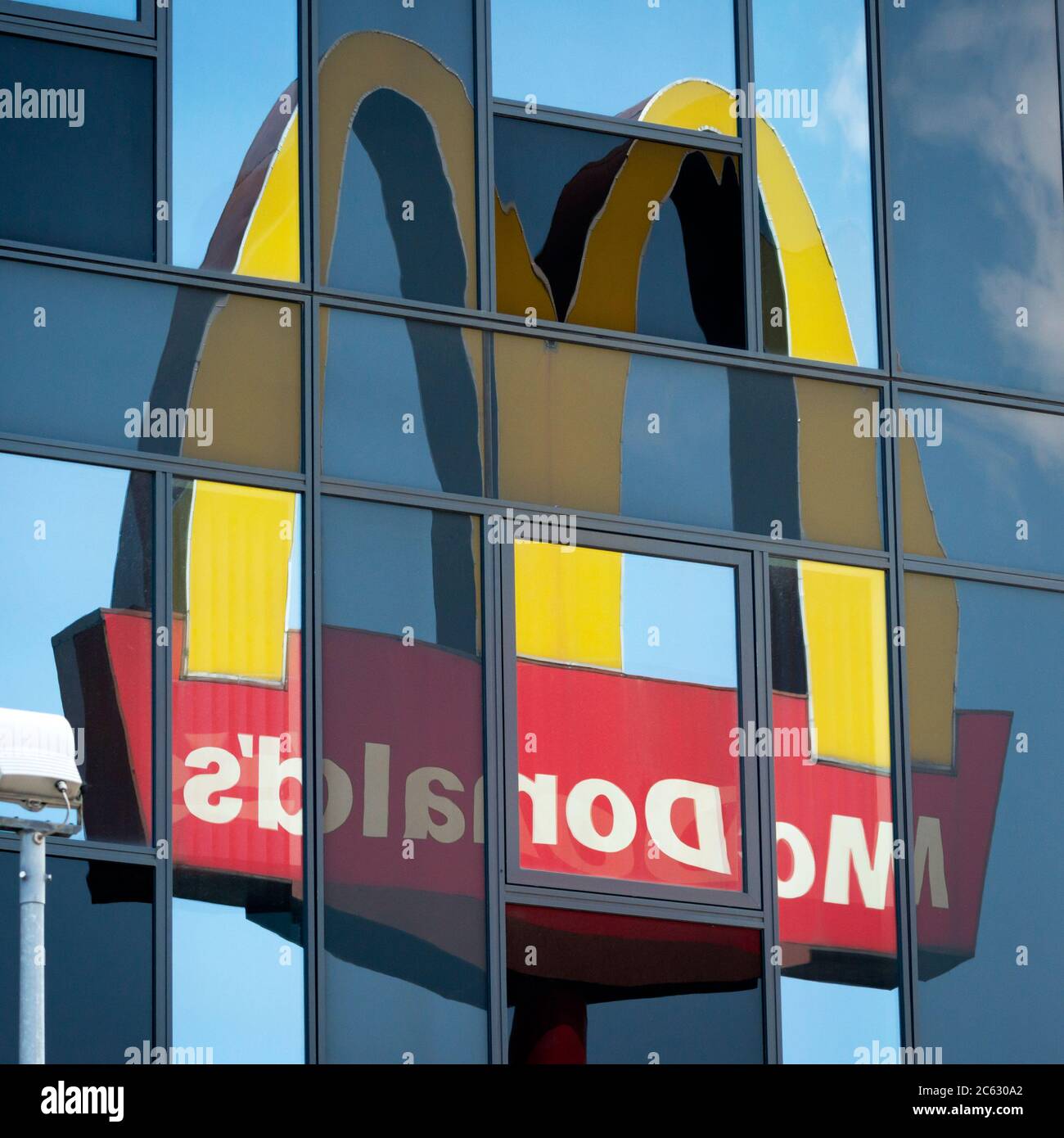 El logotipo y el cartel de McDonald's se refleja en el edificio de vidrio como inusual composición de vistas únicas Foto de stock