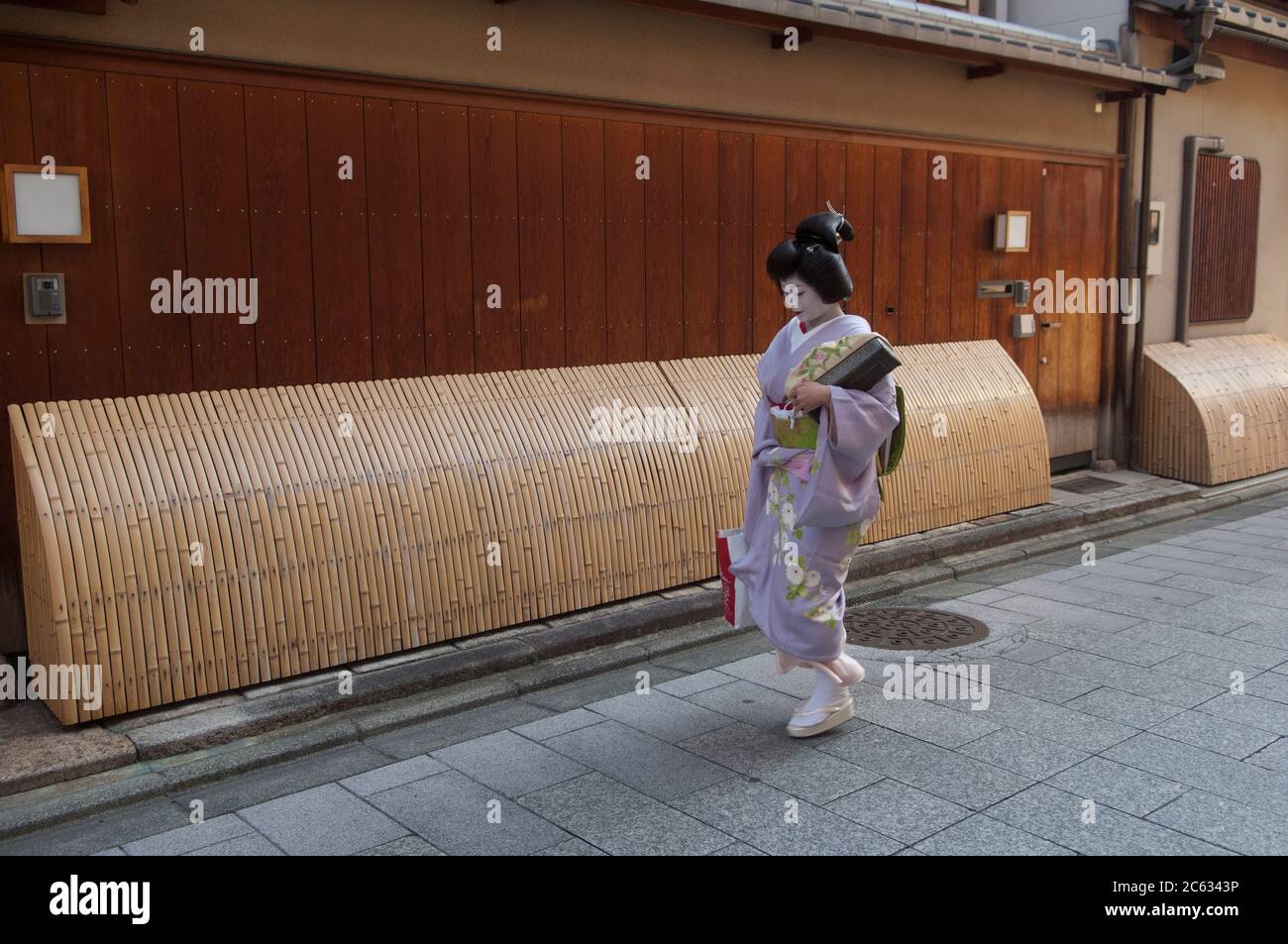 Una mujer japonesa en el vestido tradicional de Geisha caminando en una calle en el distrito de Gion, Kyoto, Japón Foto de stock