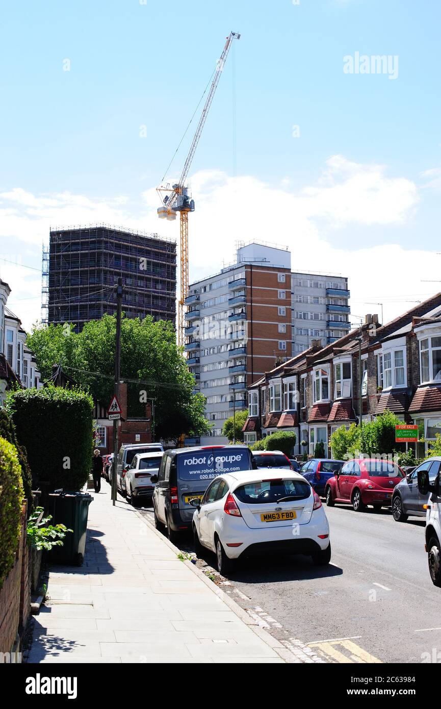 Un horizonte Suburban cambiante, una grúa de torre en el trabajo de construcción de nuevos pisos Foto de stock