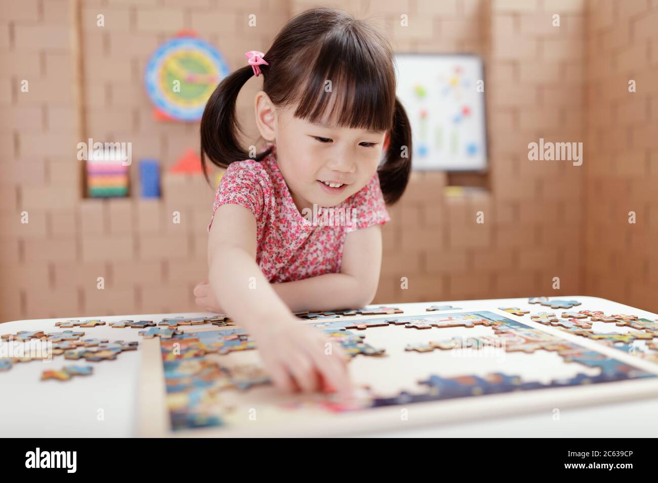 niña pequeña jugando rompecabezas de madera en casa Fotografía de stock -  Alamy