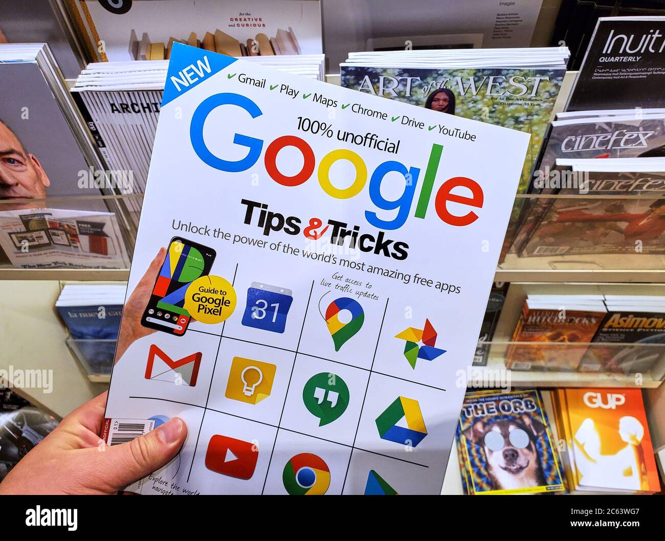 Montreal, Canadá - 30 de junio de 2020: Google Tips and Tricks revista no oficial con iconos de Google en la portada en una mano sobre una pila de revistas. Foto de stock