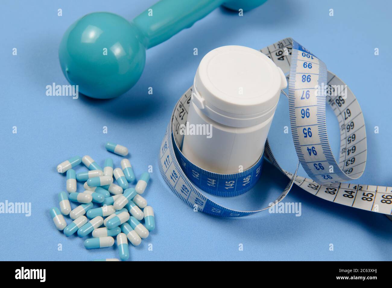 Cinta azul alrededor de una botella blanca de pastillas, tabletas sobre  fondo azul, adelgazamiento y concepto de testosterona Fotografía de stock -  Alamy