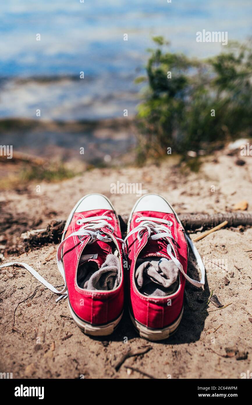Zapatos deportivos rojos de moda en la orilla arenosa cerca del embalse - el hombre dejó sus zapatos y se fue a nadar Fotografía de - Alamy