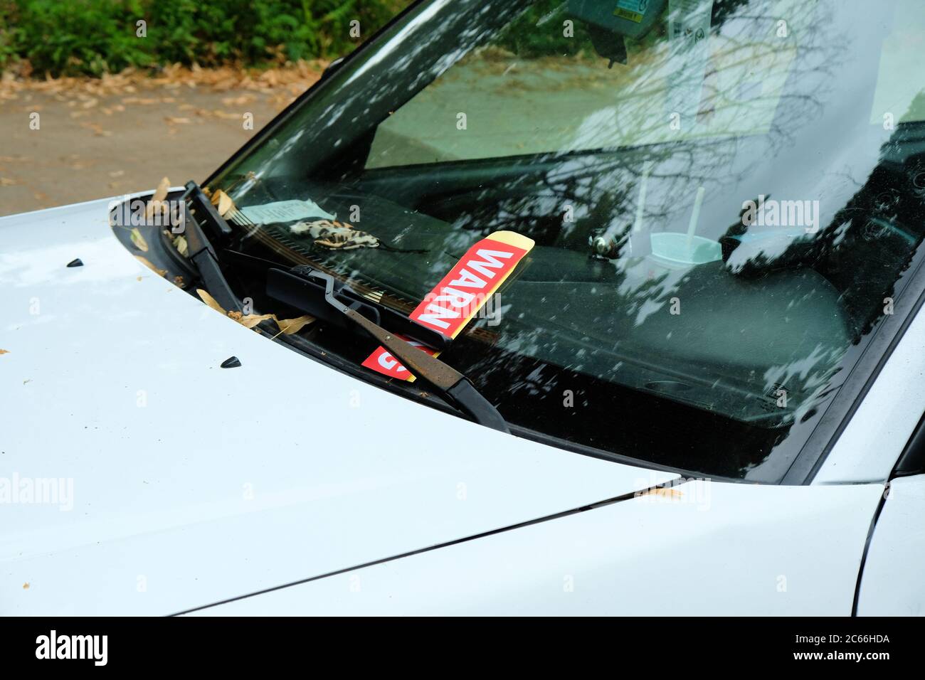Aviso de boleto rojo de violación de estacionamiento en un parabrisas debajo de la escobilla del limpiaparabrisas de un auto blanco para vehículos de estacionamiento donde no está permitido; Portland, OR. Foto de stock