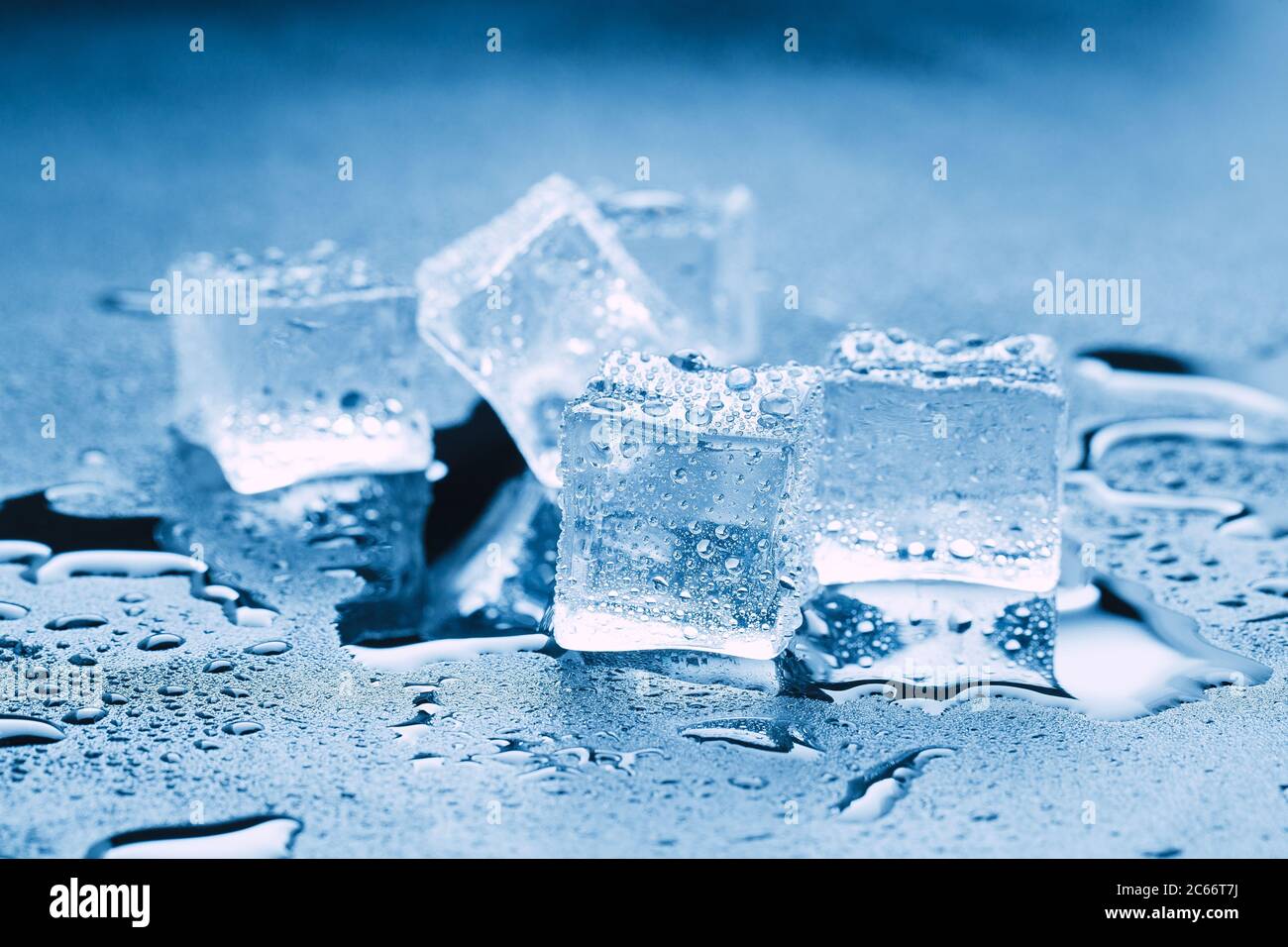 Cubitos de hielo / una colina de cubitos de hielo transparentes en un vaso  negro con gotas de agua alrededor.