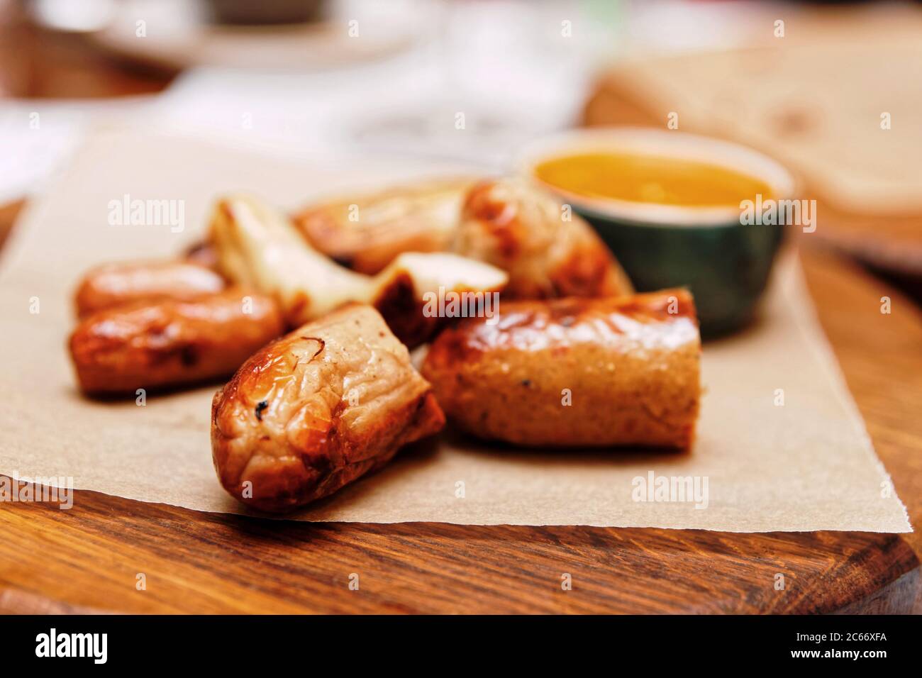 Cortar salchichas fritas a la parrilla, servido en tabla de madera, primeros planos, tonificadas Foto de stock