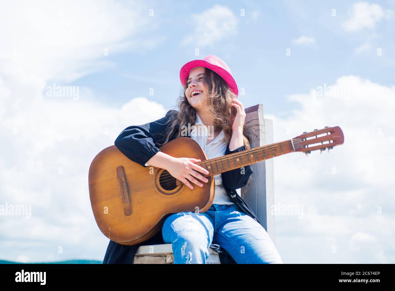 niño talentoso. estilo de música country. instrumento musical de cuerda.  tocar en guitarra acústica. niña toca guitarra le encanta la música. clases  de música. guitarra pequeña sobre fondo del cielo Fotografía de