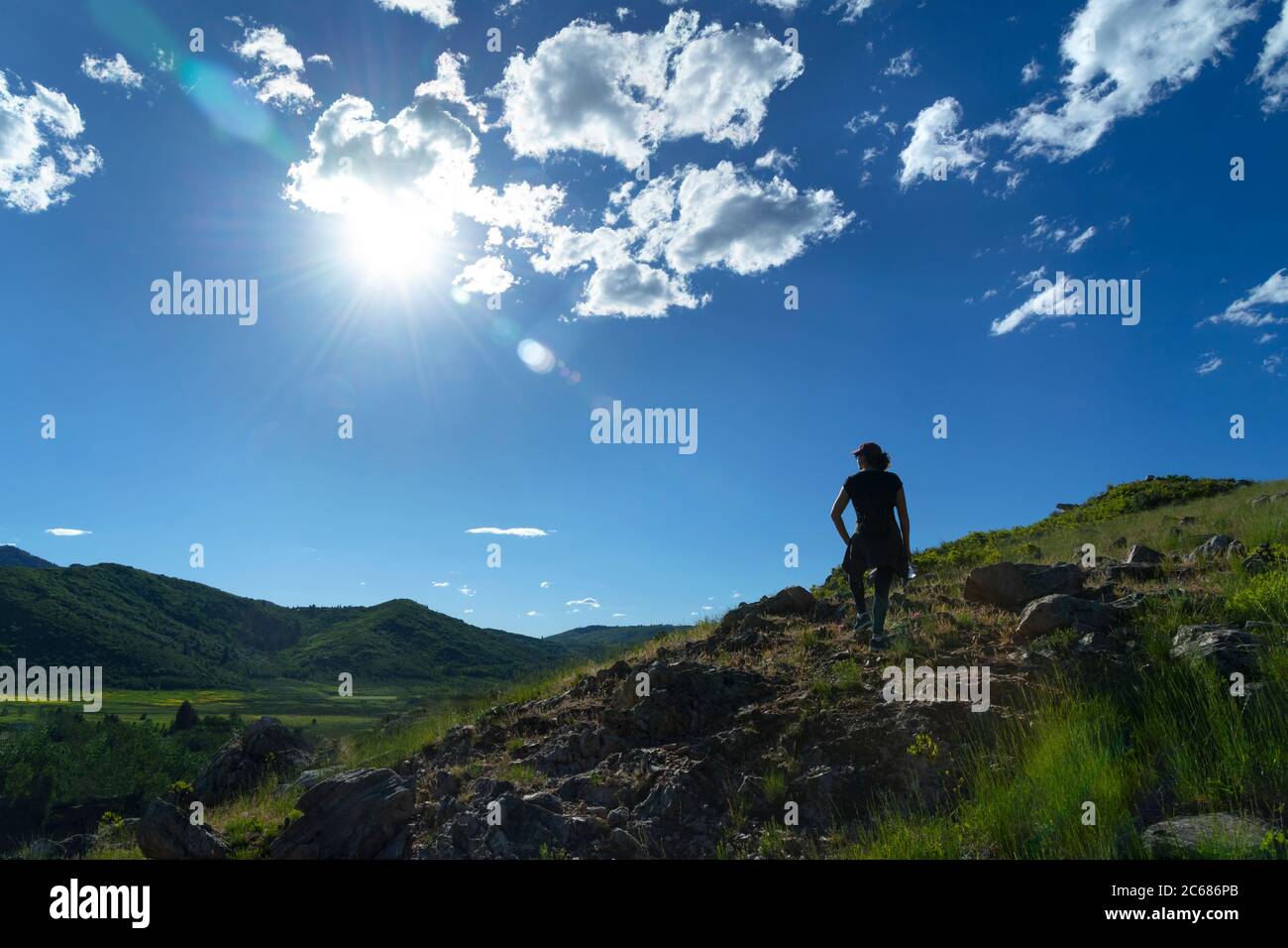 Mujer hiker en la cumbre de montaña con el sol brillos mirando hacia abajo en el valle, Utah EE.UU. Foto de stock