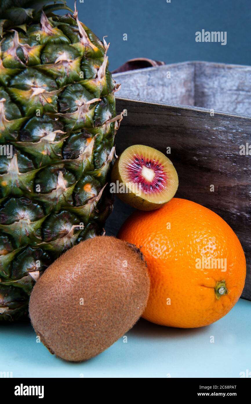 Un tiro de cerca de una piña cerca de una naranja, un kiwi lleno y un kiwi rojo picado. Foto de stock