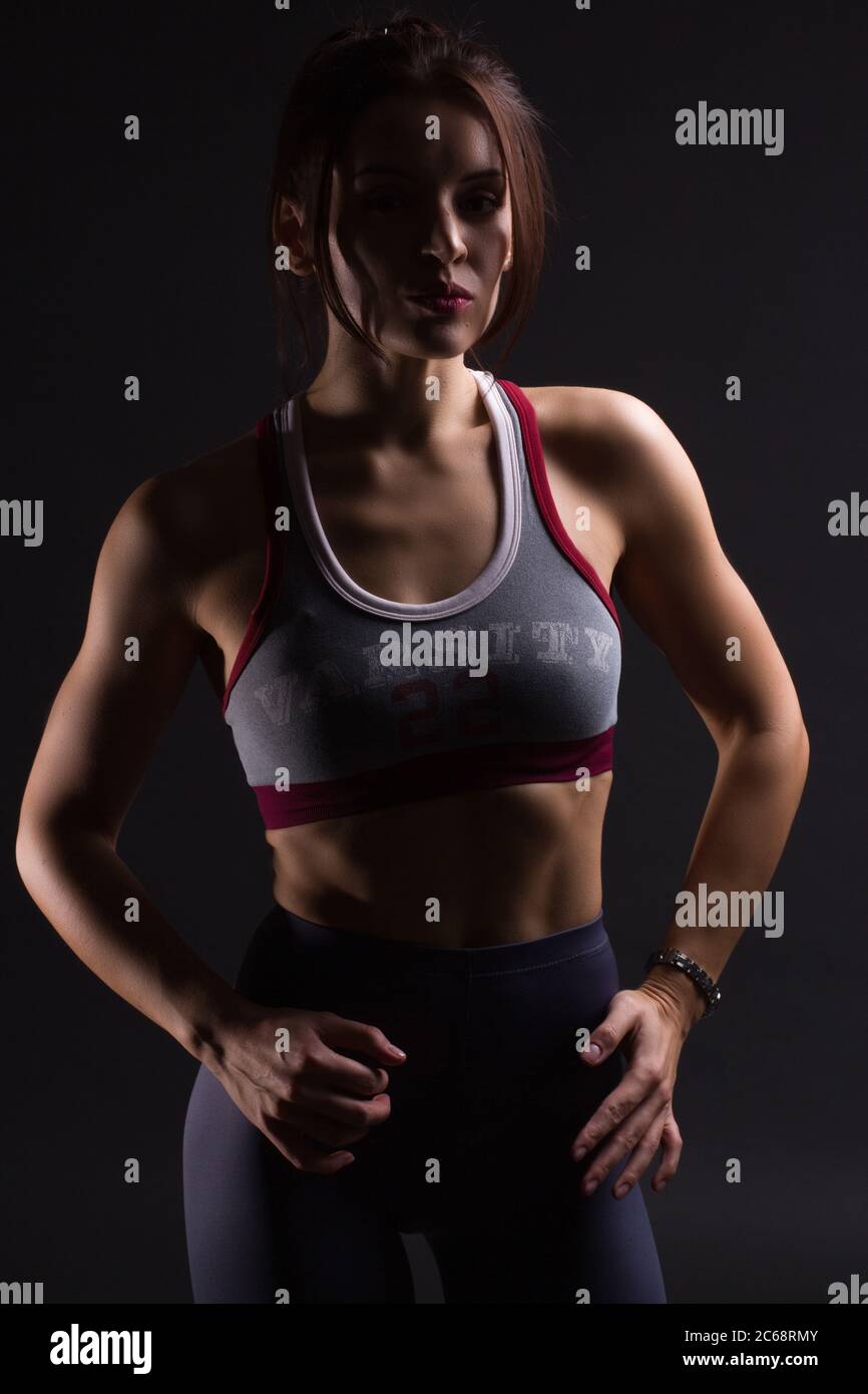 Fitness mujer joven en ropa de entrenamiento, colores oscuros retroiluminado foto Foto de stock