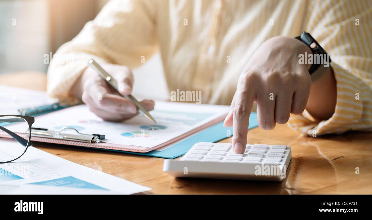 Contable o contable trabajando en el escritorio usando calculadora, concepto de finanzas de contabilidad. Foto de stock