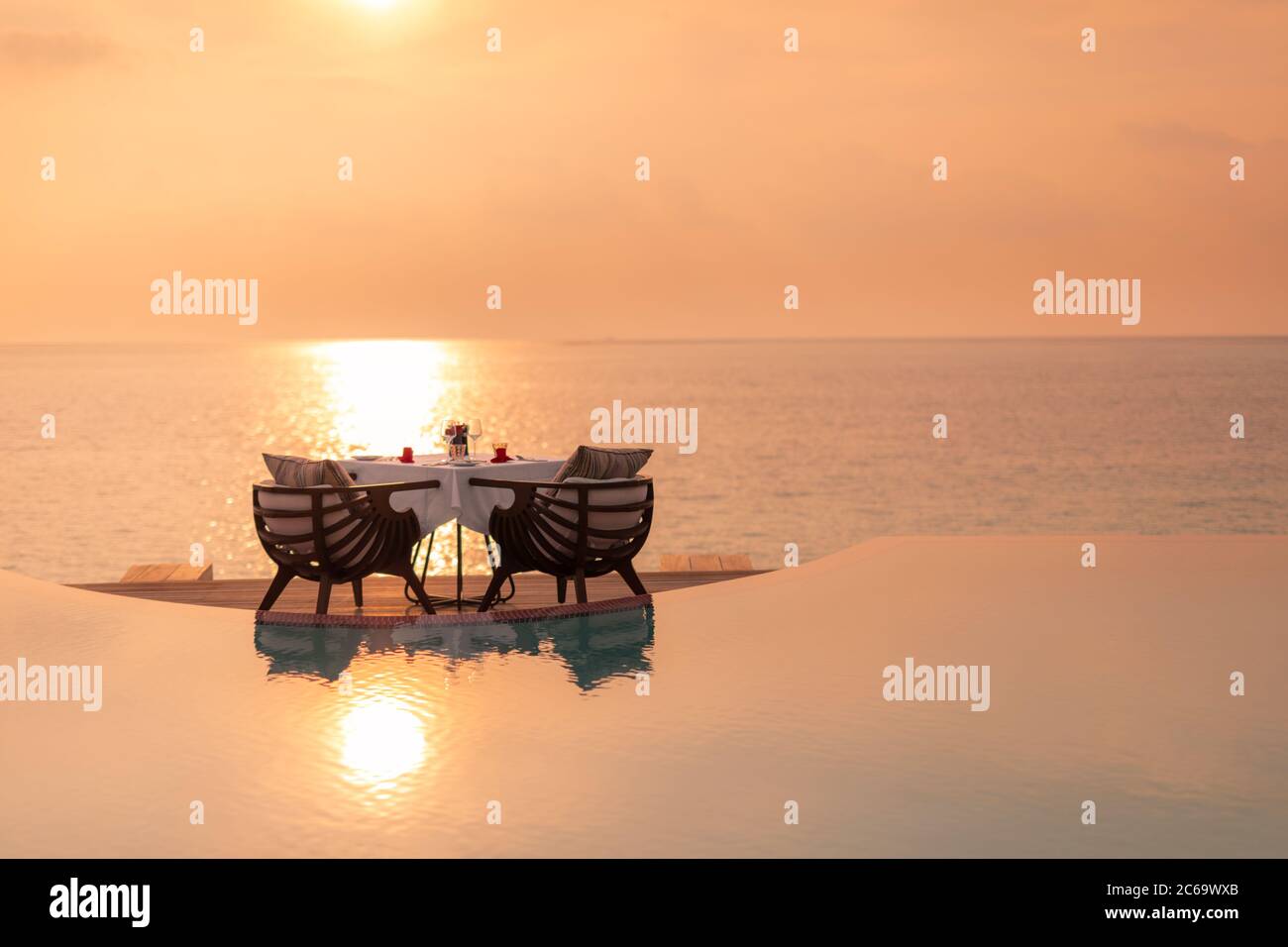 Mesa de comedor en el momento de la puesta de sol. Cena romántica en la playa, increíble reflejo del mar al atardecer. Ambiente romántico, vacaciones de viaje en pareja Foto de stock