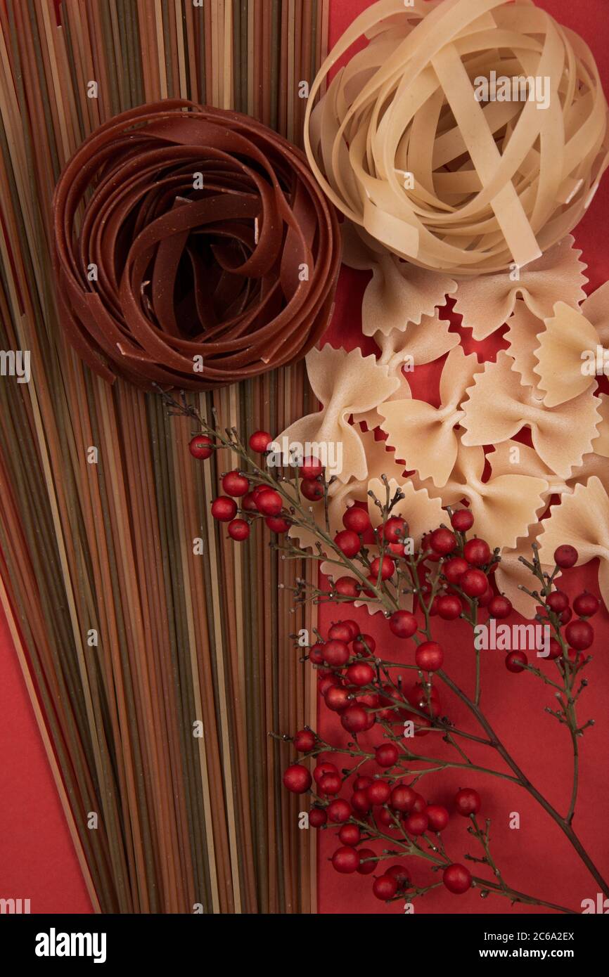 Pasta larga y marrón en diferentes formas y colores con una flor roja. Foto de stock