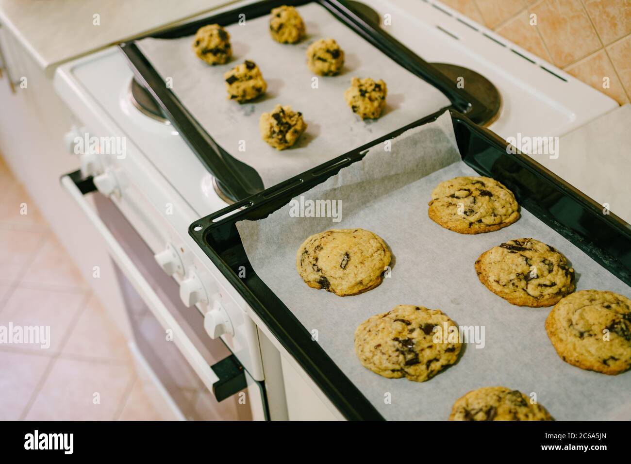 Dos bandejas de horno en la mesa de la cocina - con galletas americanas  cocinadas y bolas de masa cruda Fotografía de stock - Alamy