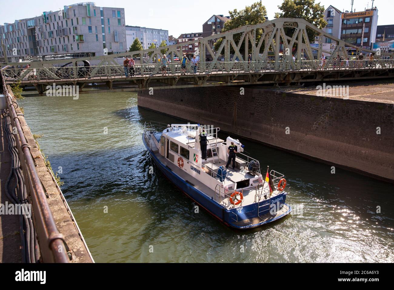 El barco de policía bajo el puente colgante entra en el puerto de Rheinau, Colonia, Alemania. Polizeibboot faehrt unter der Drehbruecke in den Rheinauhafen ein, Koeln, Foto de stock