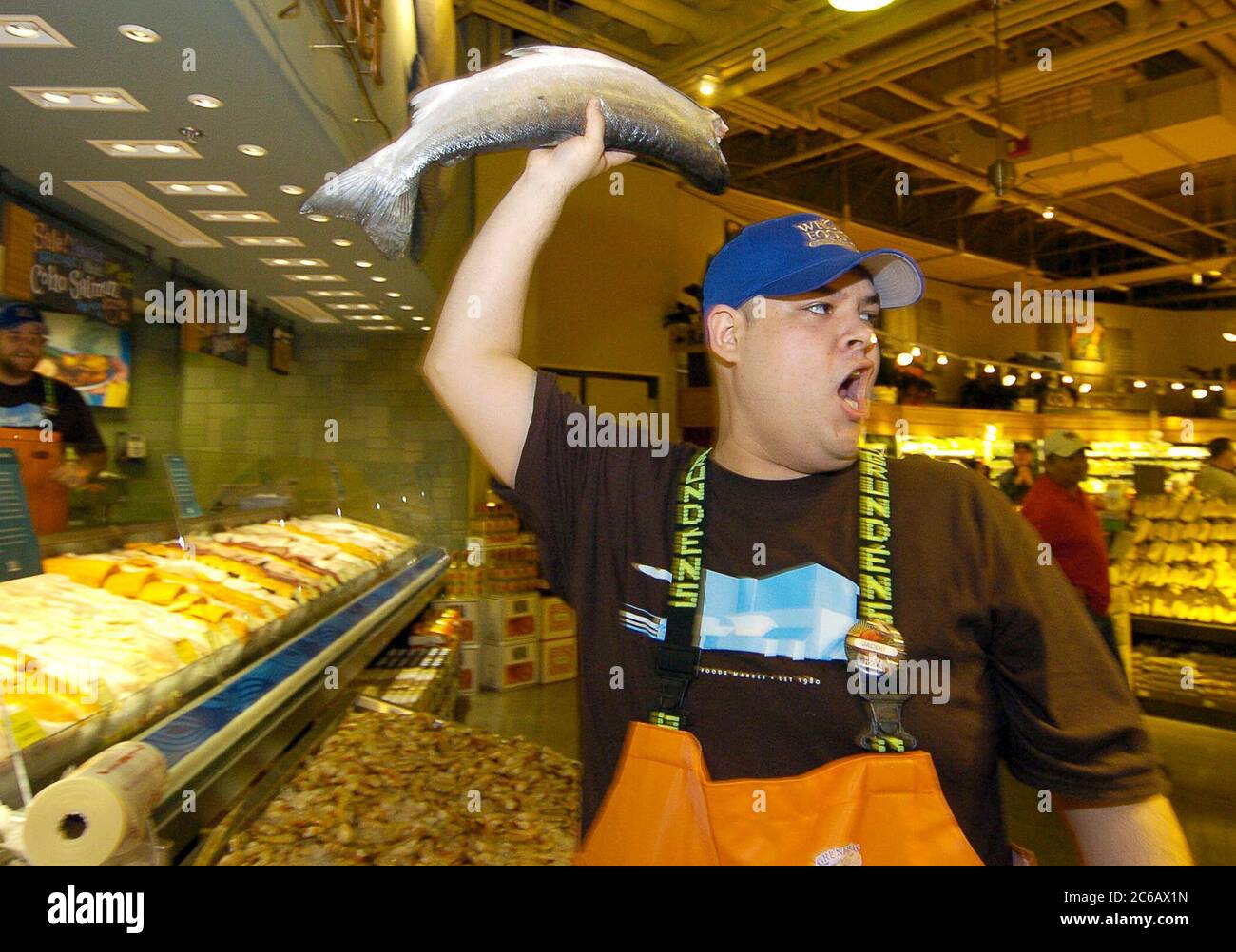 Austin, Texas, EE.UU., 3 de marzo de 2005: Un empleado del mercado de pescado de Whole Foods sostiene en alto un pescado fresco durante la gran inauguración de la tienda insignia de Whole Foods de 80.000 pies cuadrados y la sede corporativa en el Distrito Emergente del Mercado de Austin. La cadena nacional cuenta con 167 tiendas y es el líder mundial en supermercados naturales y orgánicos. © Bob Daemmrich Foto de stock