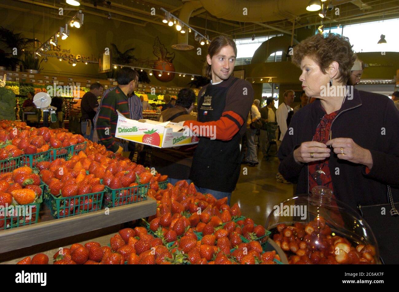 Austin, Texas, EE.UU., 3 2005 de marzo: El empleado de productos agrícolas habla con el comprador en la exhibición de fresas frescas durante la gran inauguración de la tienda insignia de Whole Foods de 80.000 pies cuadrados y la sede corporativa en el emergente Distrito de Mercado de Austin. La cadena nacional cuenta con 167 tiendas y es el líder mundial en supermercados naturales y orgánicos. © Bob Daemmrich Foto de stock