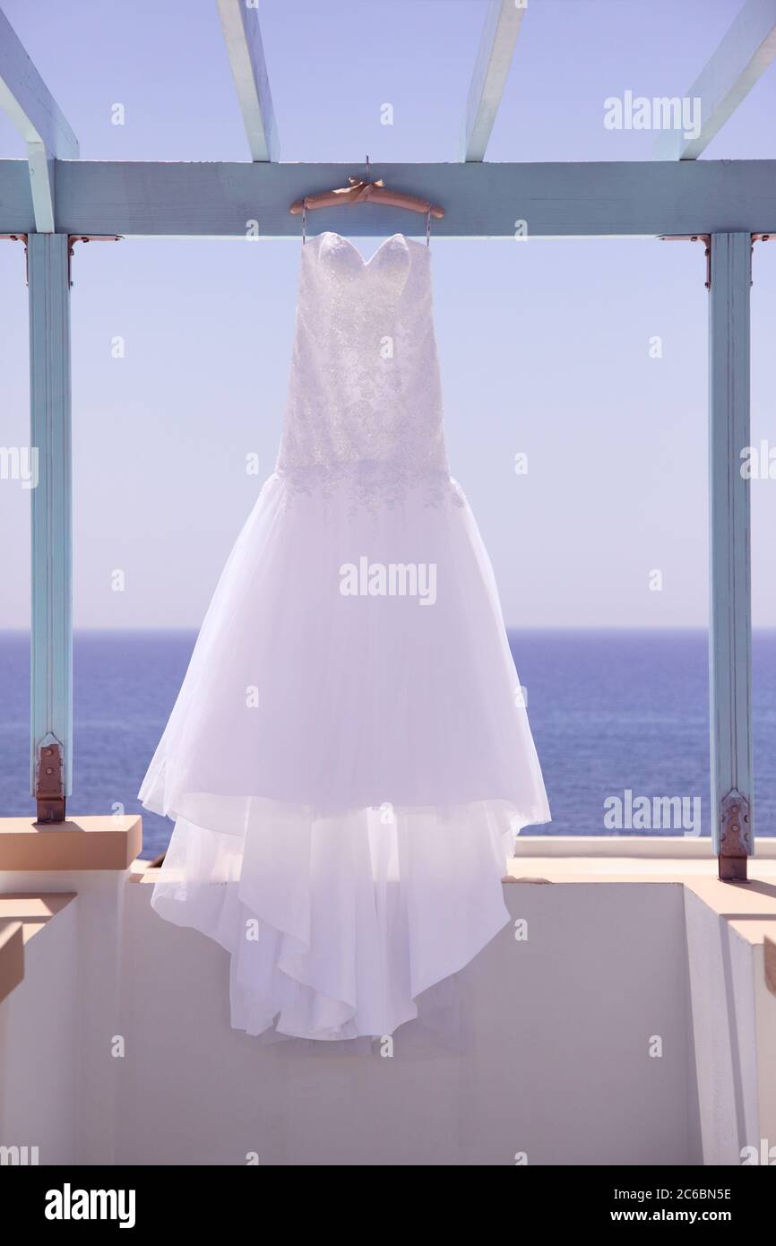 Blanco vestido de boda nupcial colgando frente al Mar Mediterráneo. Ilustrativo del concepto de bodas en el extranjero y la boda de destino Foto de stock