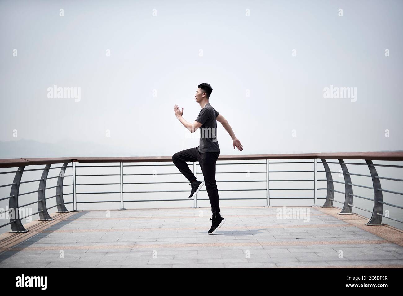 joven asiático adulto ejercitando al aire libre junto al mar Foto de stock