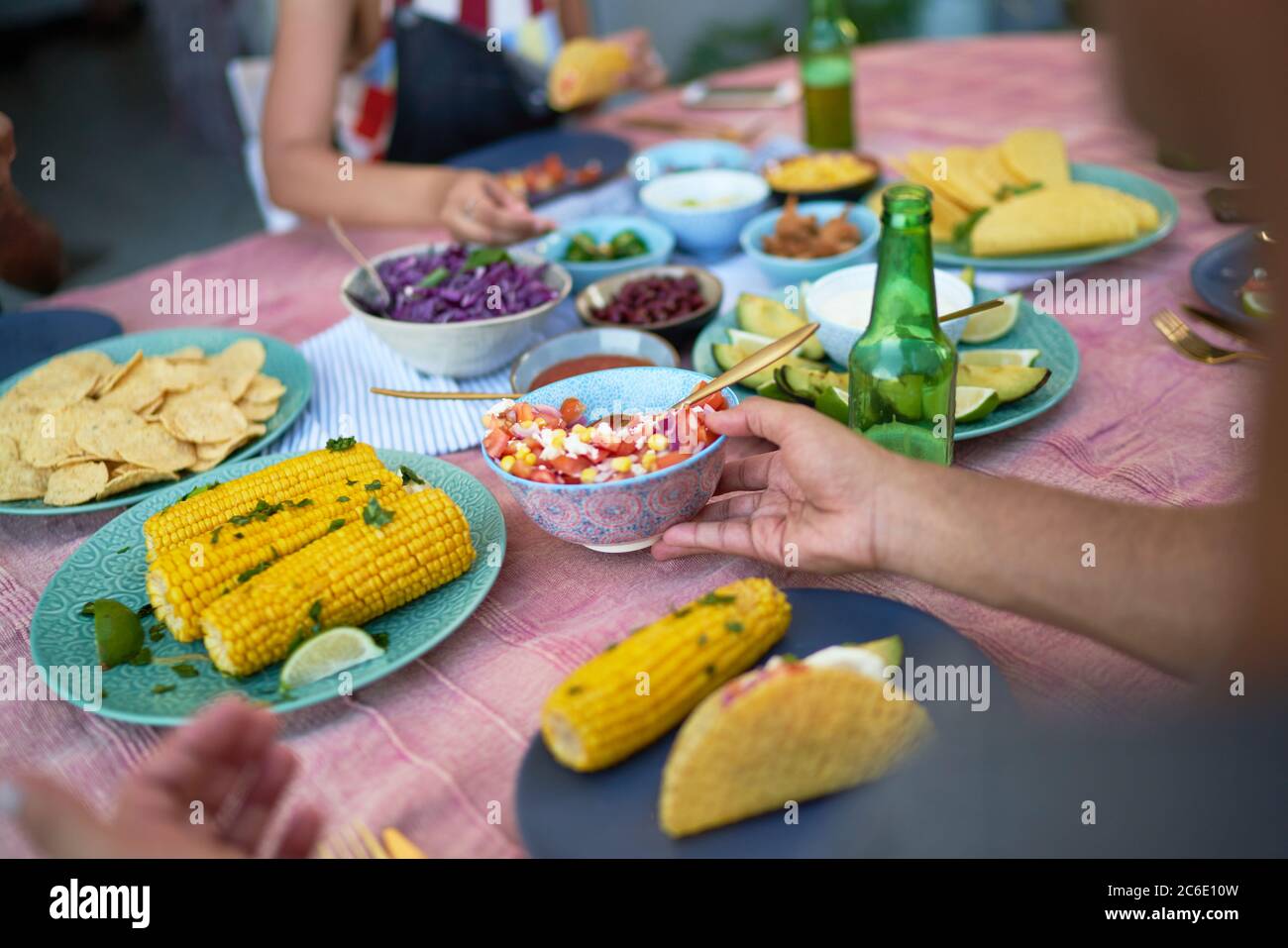 Amigos comiendo tacos y maíz en la mesa del patio Foto de stock