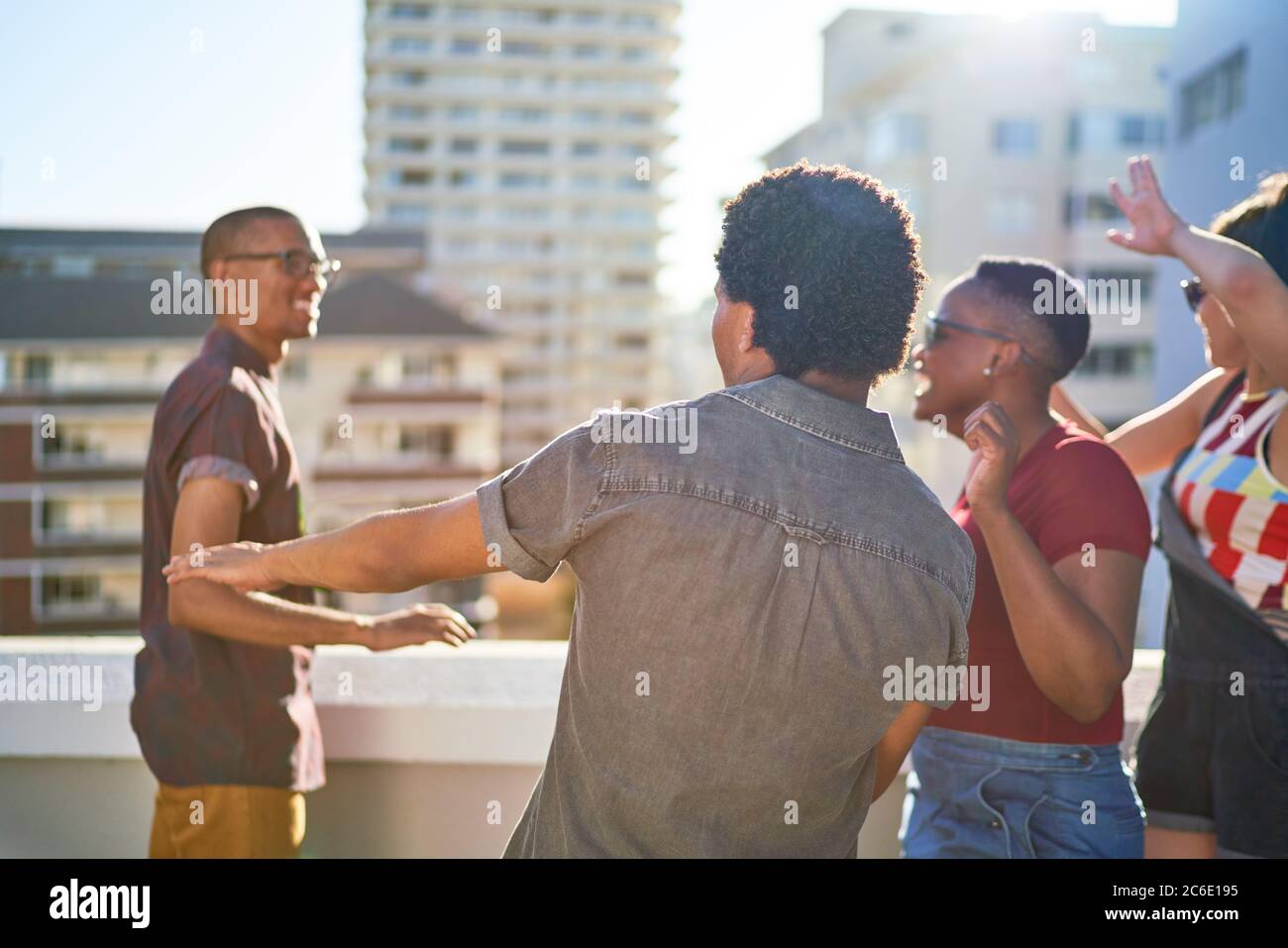 Jóvenes amigos despreocupados bailando en la soleada azotea urbana Foto de stock
