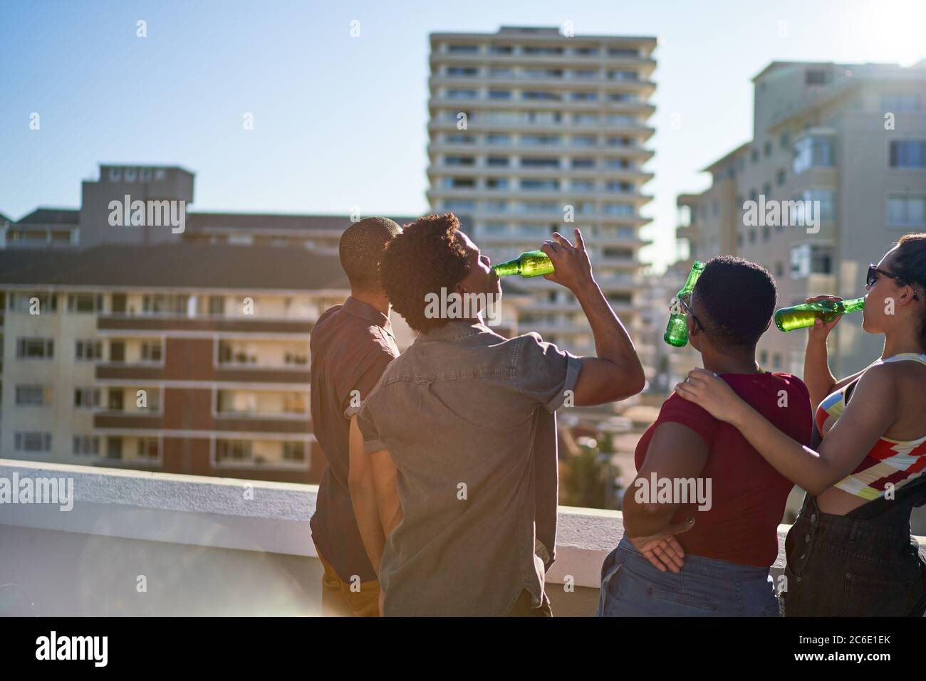 Jóvenes amigos bebiendo cerveza en la soleada azotea urbana Foto de stock