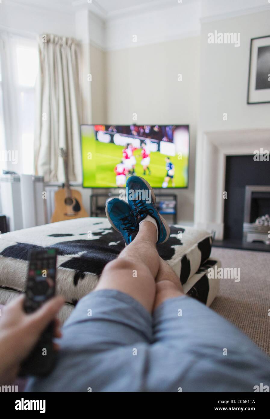 Hombre del POV mirando partido de fútbol en la TV en la sala de estar Foto de stock