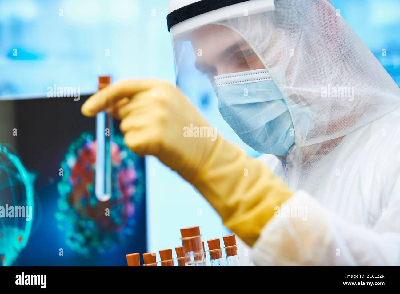 Cierre a un científico masculino con tubo de ensayo que estudia la vacuna contra el coronavirus Foto de stock