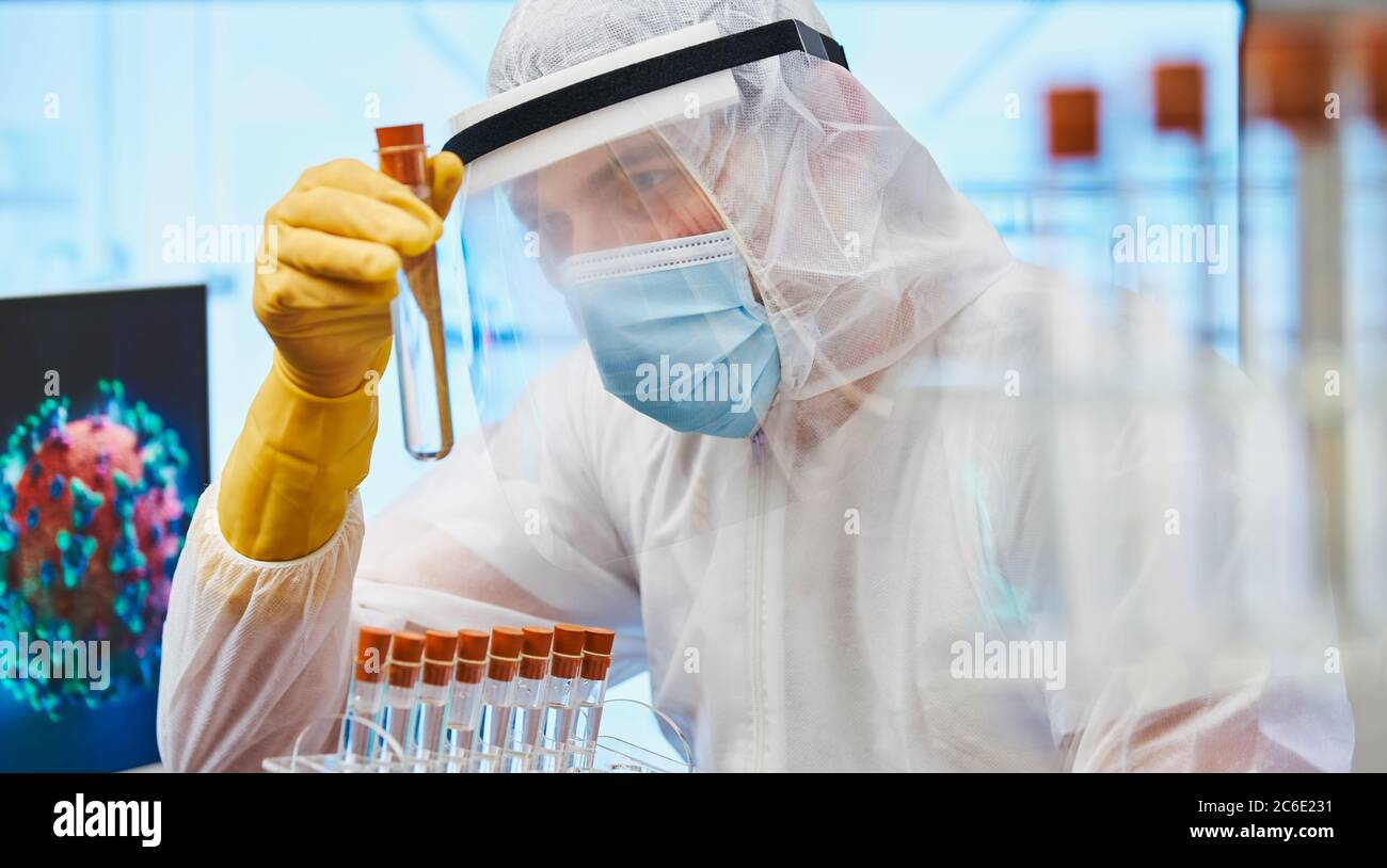 Científico masculino enfocado con tubo de ensayo que investiga el coronavirus Foto de stock
