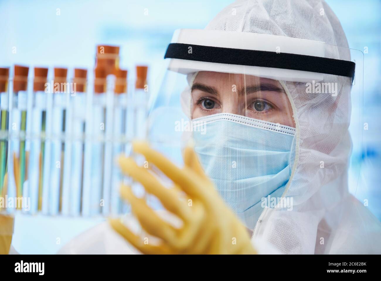 Mujer científica en traje limpio examinando tubos de ensayo Foto de stock