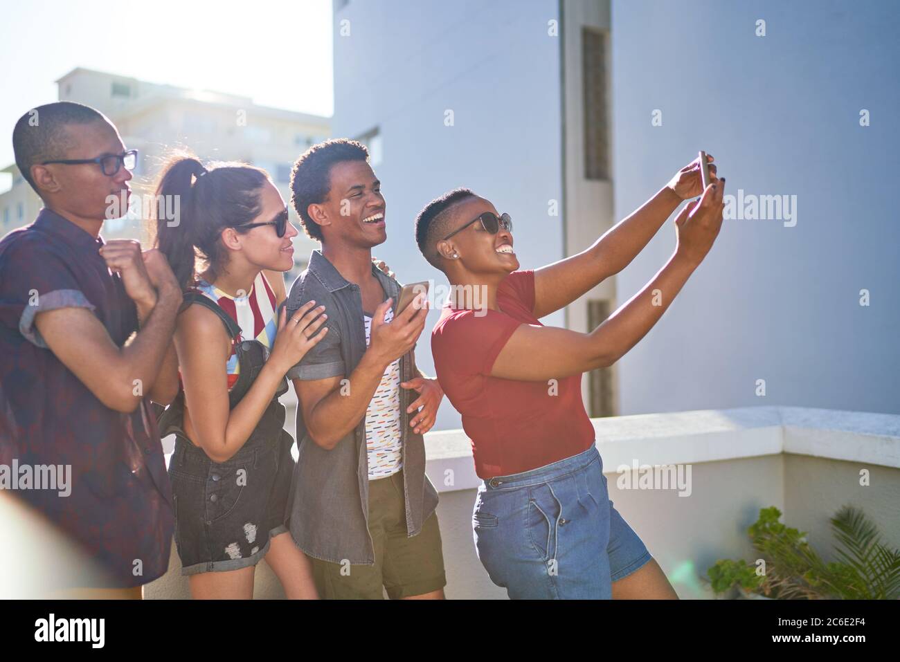 Felices amigos jóvenes tomando selfie en el soleado balcón urbano Foto de stock