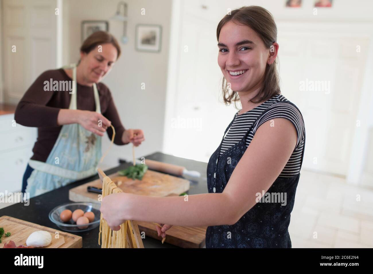 Retrato feliz adolescente haciendo pasta casera con la madre en casa Foto de stock