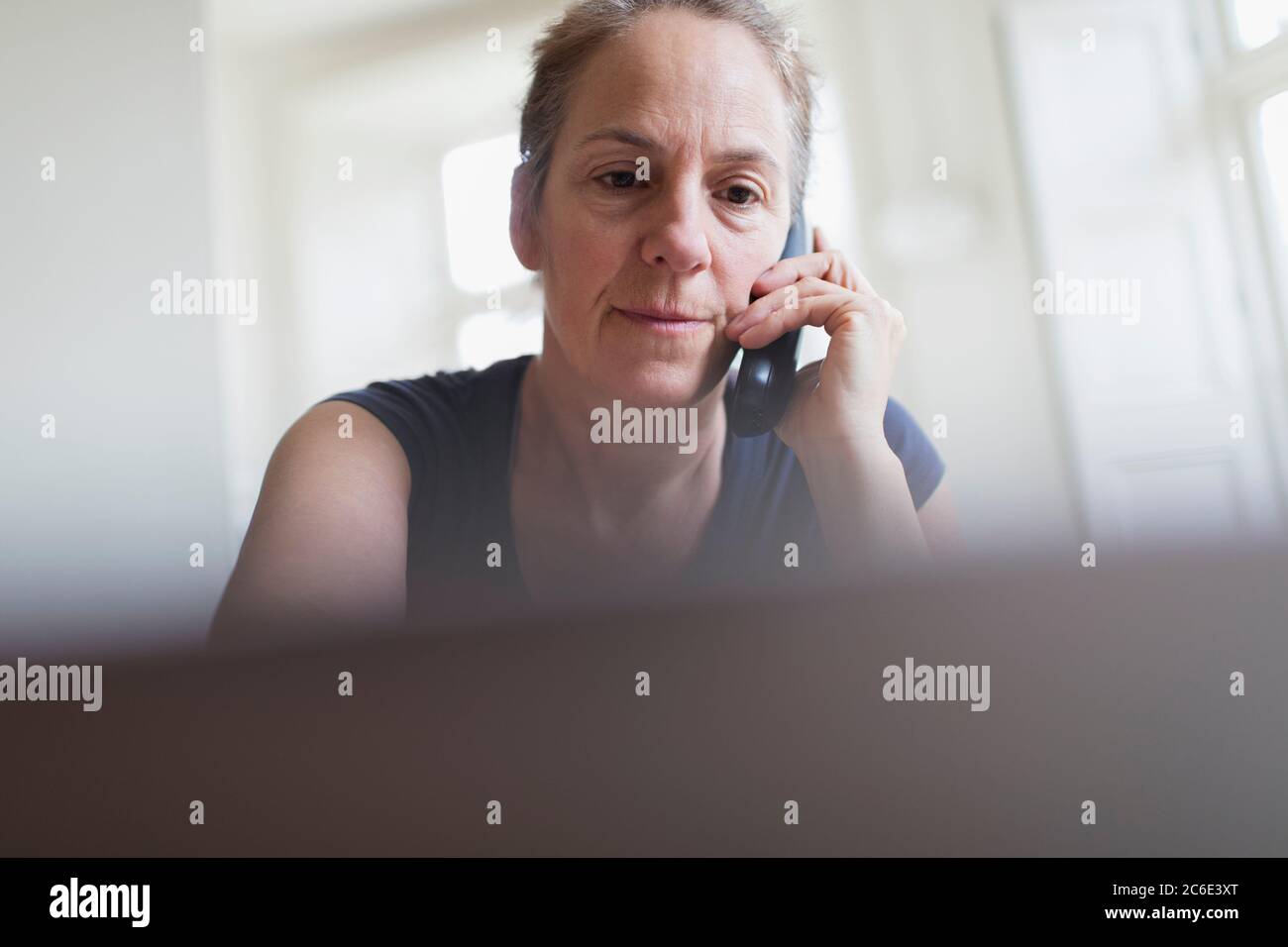 Mujer hablando por teléfono y trabajando en el ordenador portátil Foto de stock