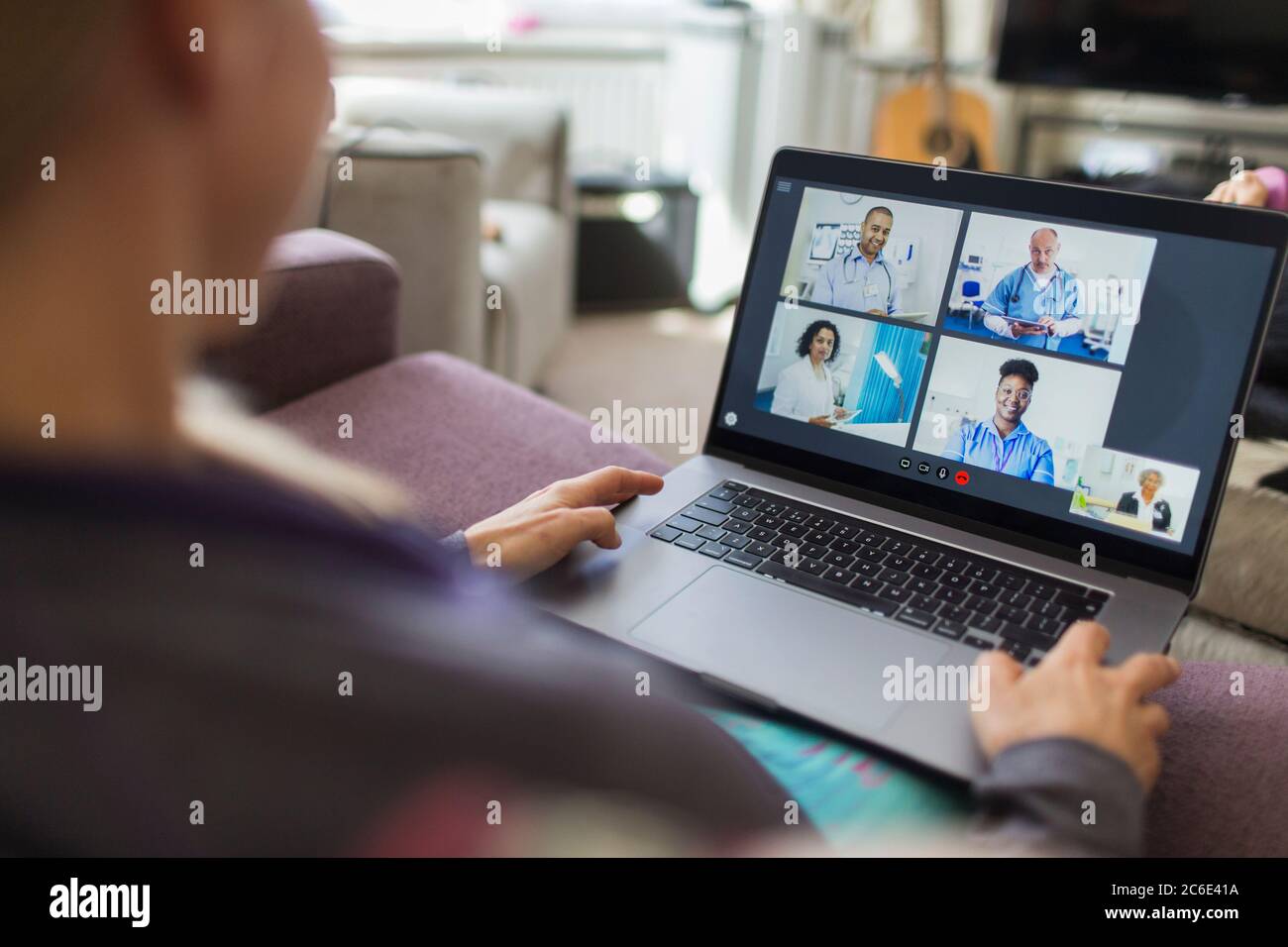 Mujer con portátil video charlando con los médicos desde el sofá Foto de stock