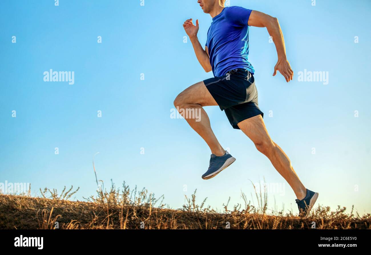 atleta corredor correr cuesta arriba en fondo claro cielo azul Foto de stock