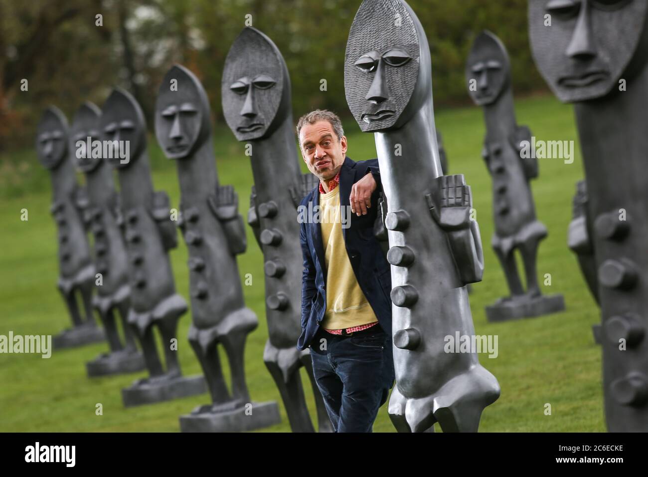 El artista Zak Ove en medio de sus 80 figuras de grafito idénticas en Yorkshire Sculpture Park en Wakefield, Reino Unido. Las esculturas de dos metros de altura son parte Foto de stock