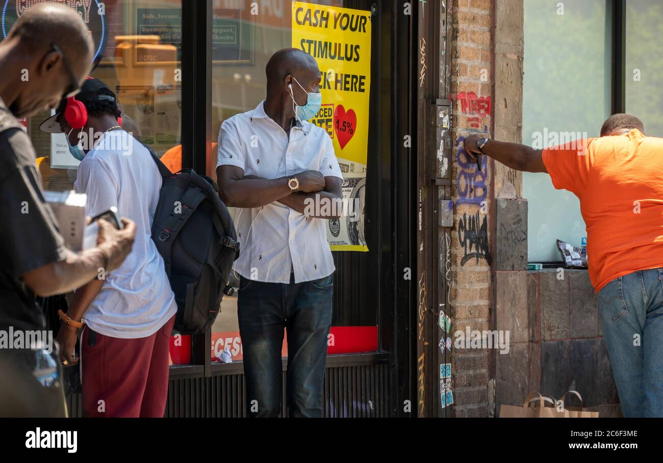 Los clientes se alinean fuera de un negocio de cobro de cheques en Harlem, Nueva York, el sábado 4 de julio de 2020, que anuncia que se hacen efectivo los cheques de estímulo. (© Richard B. Levine) Foto de stock