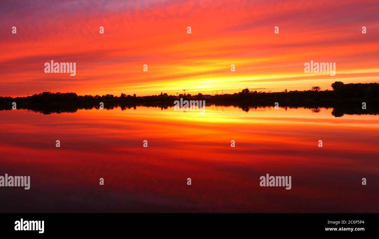 Simetría del cielo en un lago al amanecer. Nubes que se reflejan en el agua. Paisaje vacacional junto al mar. Tranquila y relajante escena con un hermoso colorido Foto de stock