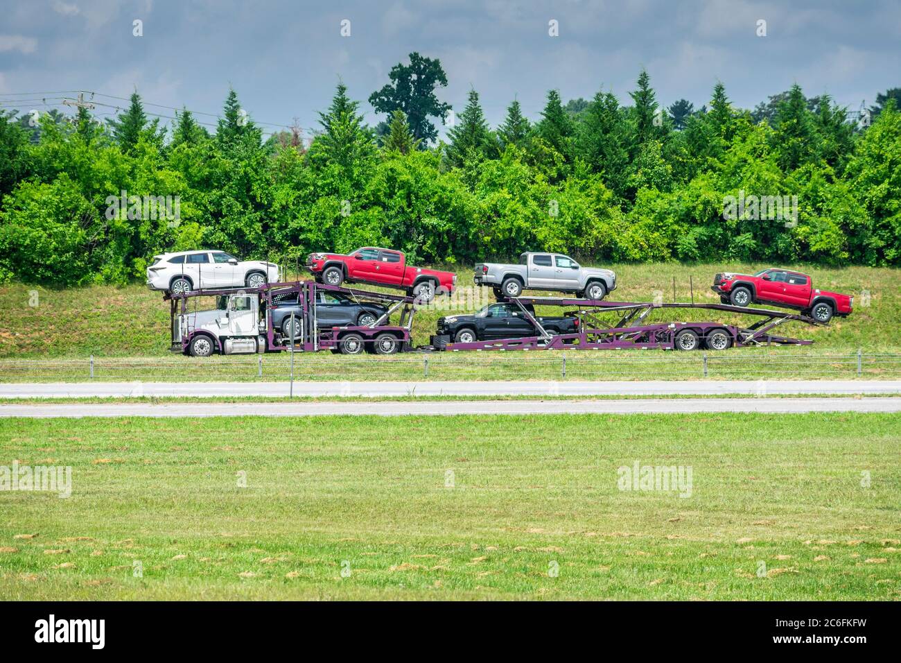 Camión de transporte de automóviles fotografiado a distancia en un caluroso día de verano. Las olas de calor del pavimento crean un ligero efecto brillante. Foto de stock