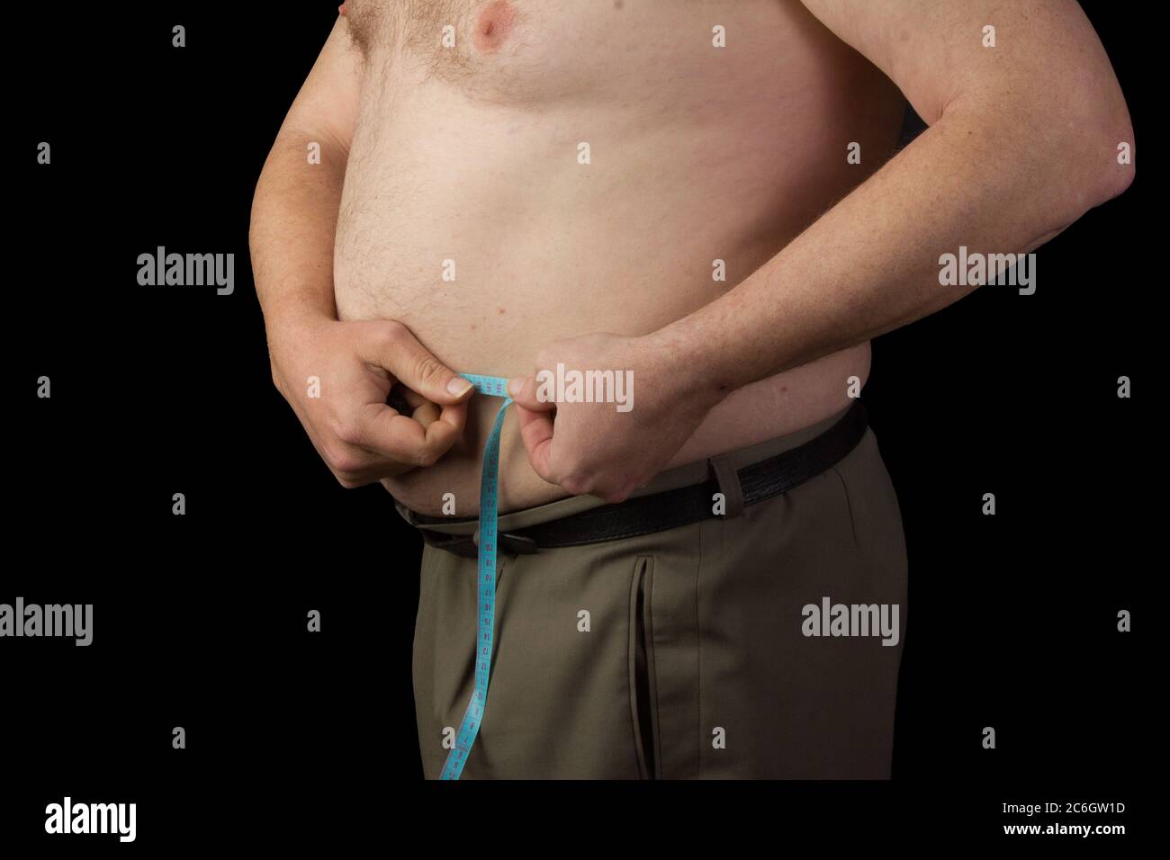 Hombre gordo sosteniendo una cinta métrica, mida su abdomen. Pérdida de peso. Foto sobre fondo negro aislado Foto de stock